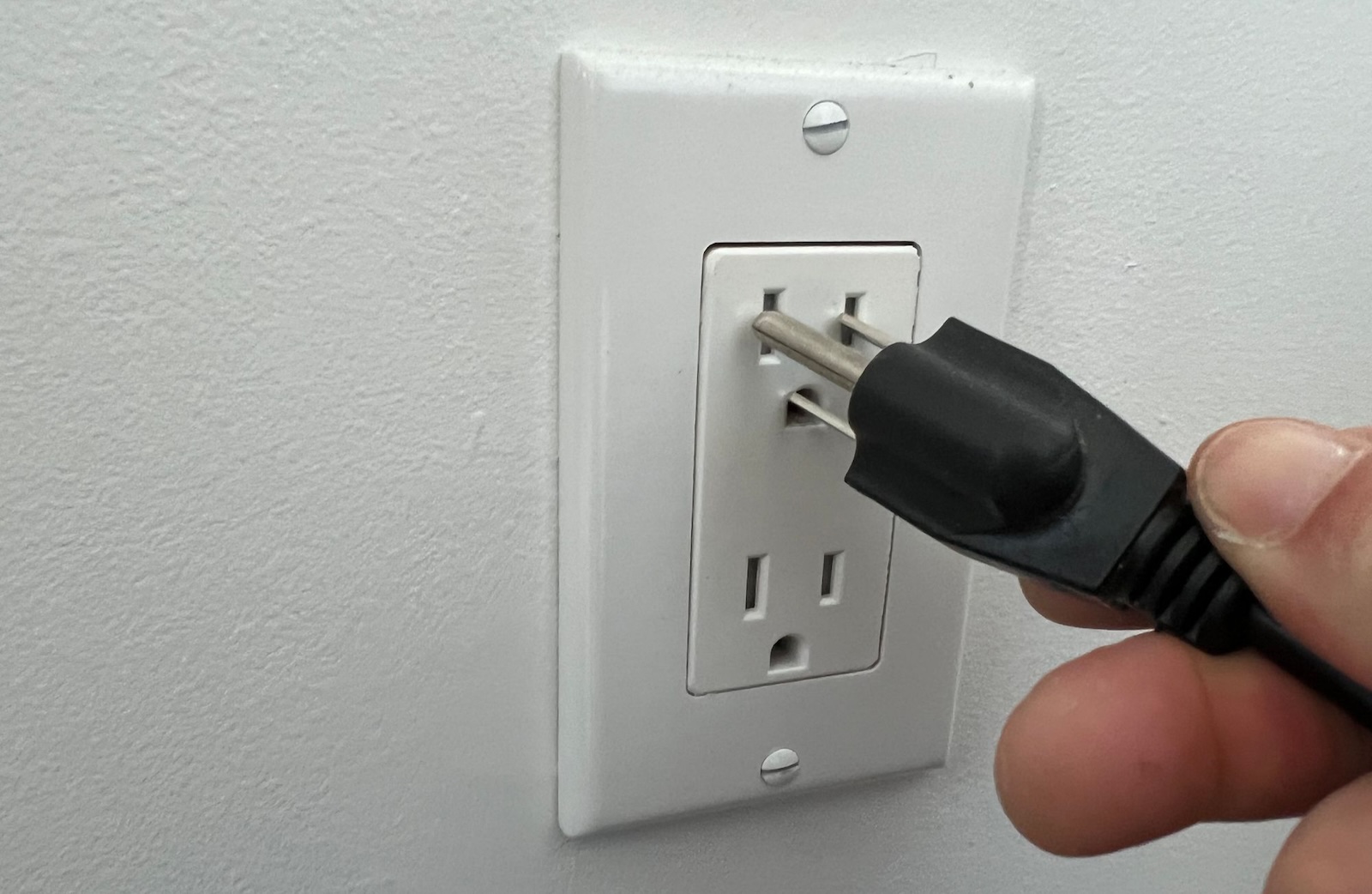 A hand plugging a plug into a socket